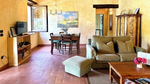 Una sala de estar acogedora con techo de madera, una zona de comedor con mesa y sillas, y un sofá con cojín.