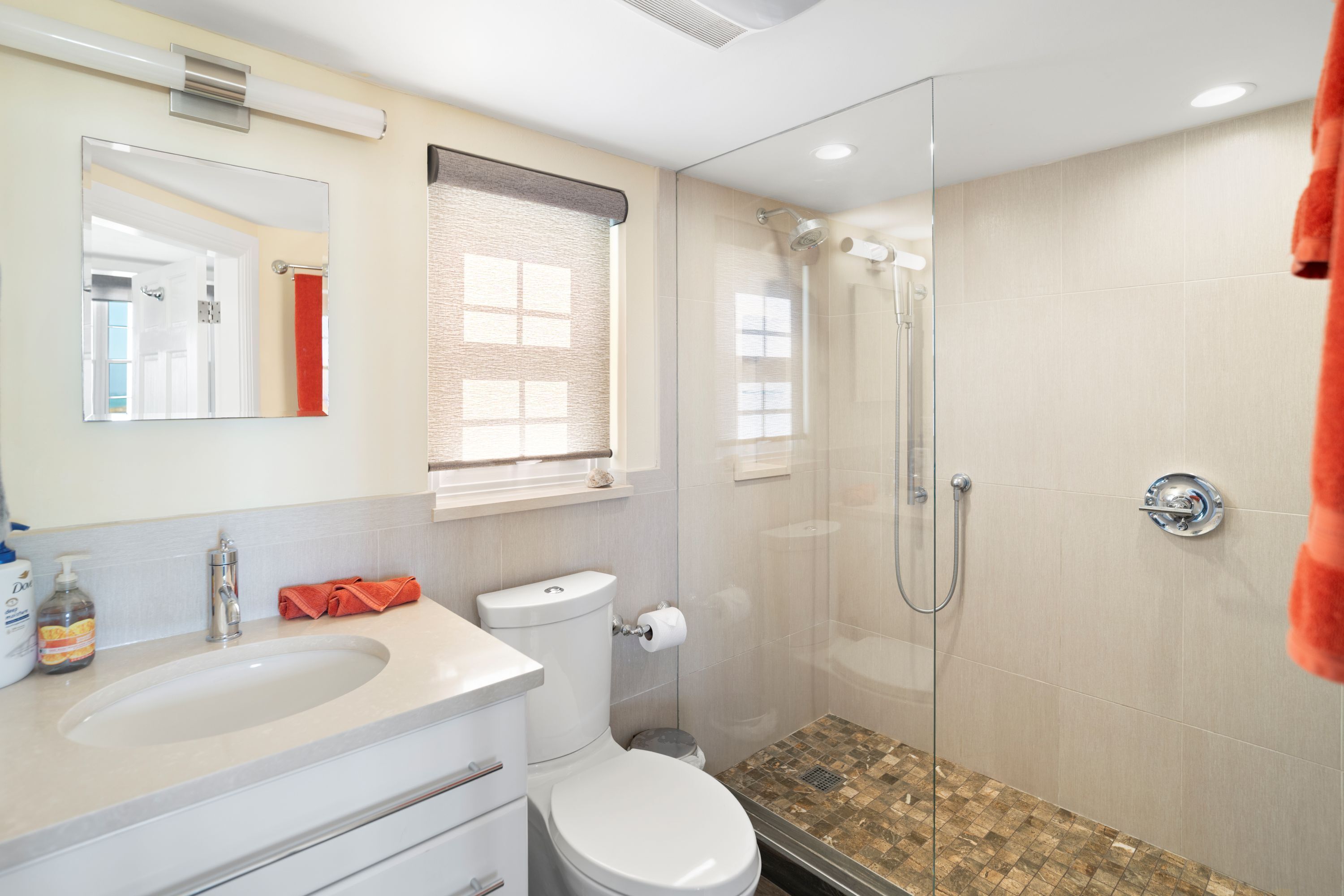 Un baño moderno con ducha acristalada, lavamanos blanco y un inodoro.
