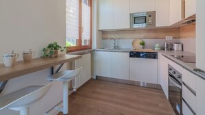 A modern kitchen with white cabinets, a microwave, a dishwasher, and a wooden countertop.