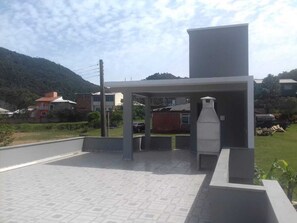 Uma área de estar moderna ao ar livre, com churrasqueira, assentos e vista para o bairro.
