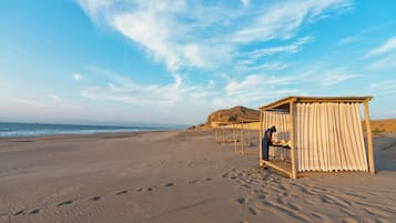 A beach with a wooden structure and a person working near it.