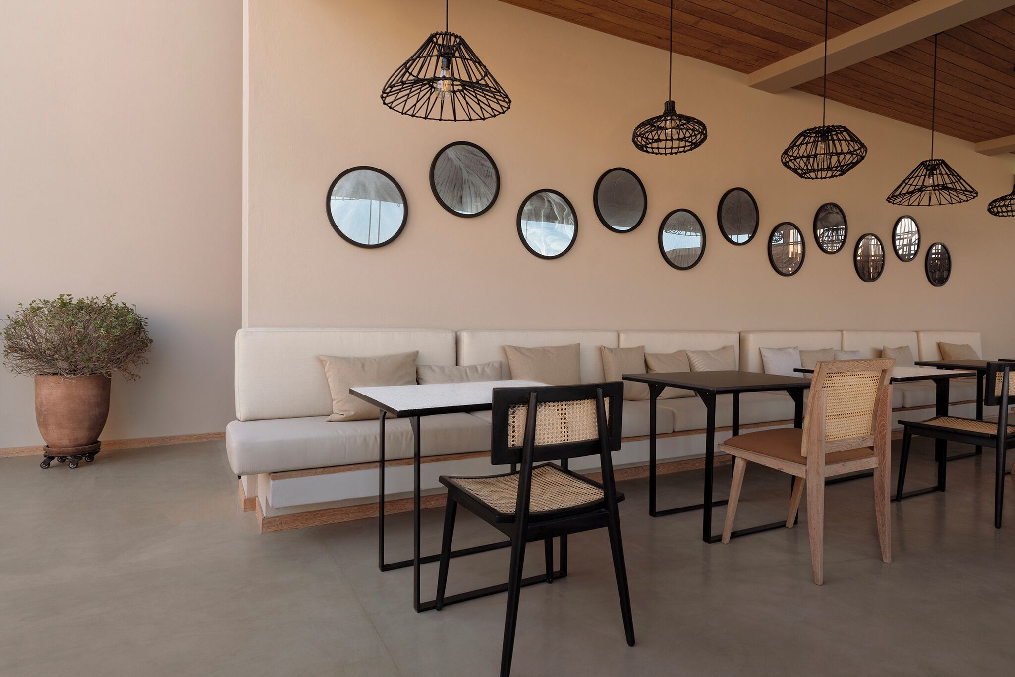 A modern interior with a sofa, dining tables, chairs, and hanging pendant lights.
