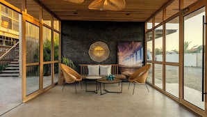 A modern interior with a dining area, wicker chairs, a round table, and a large abstract painting on the wall.