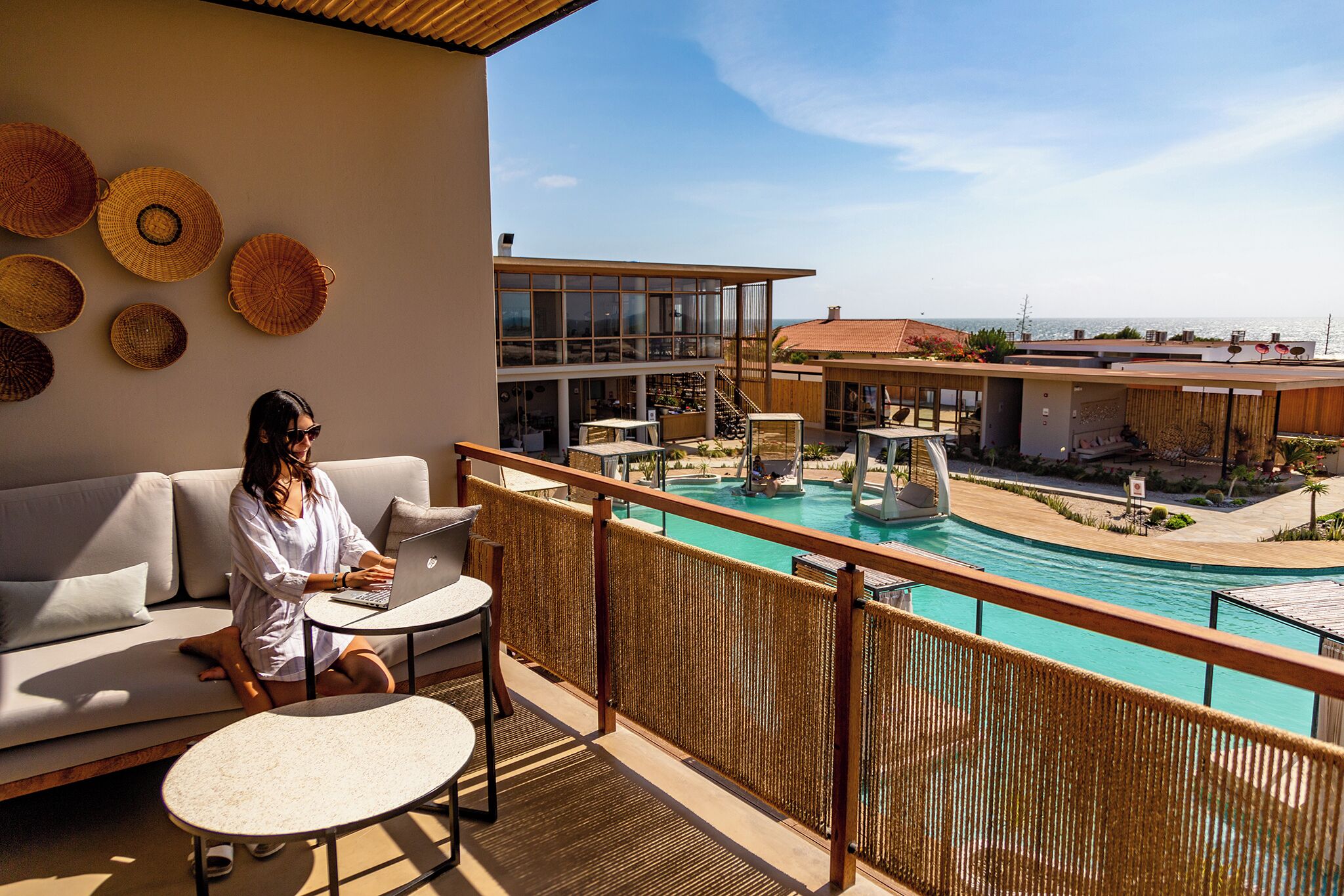 A balcony with a view of a pool, a sofa, and a laptop.