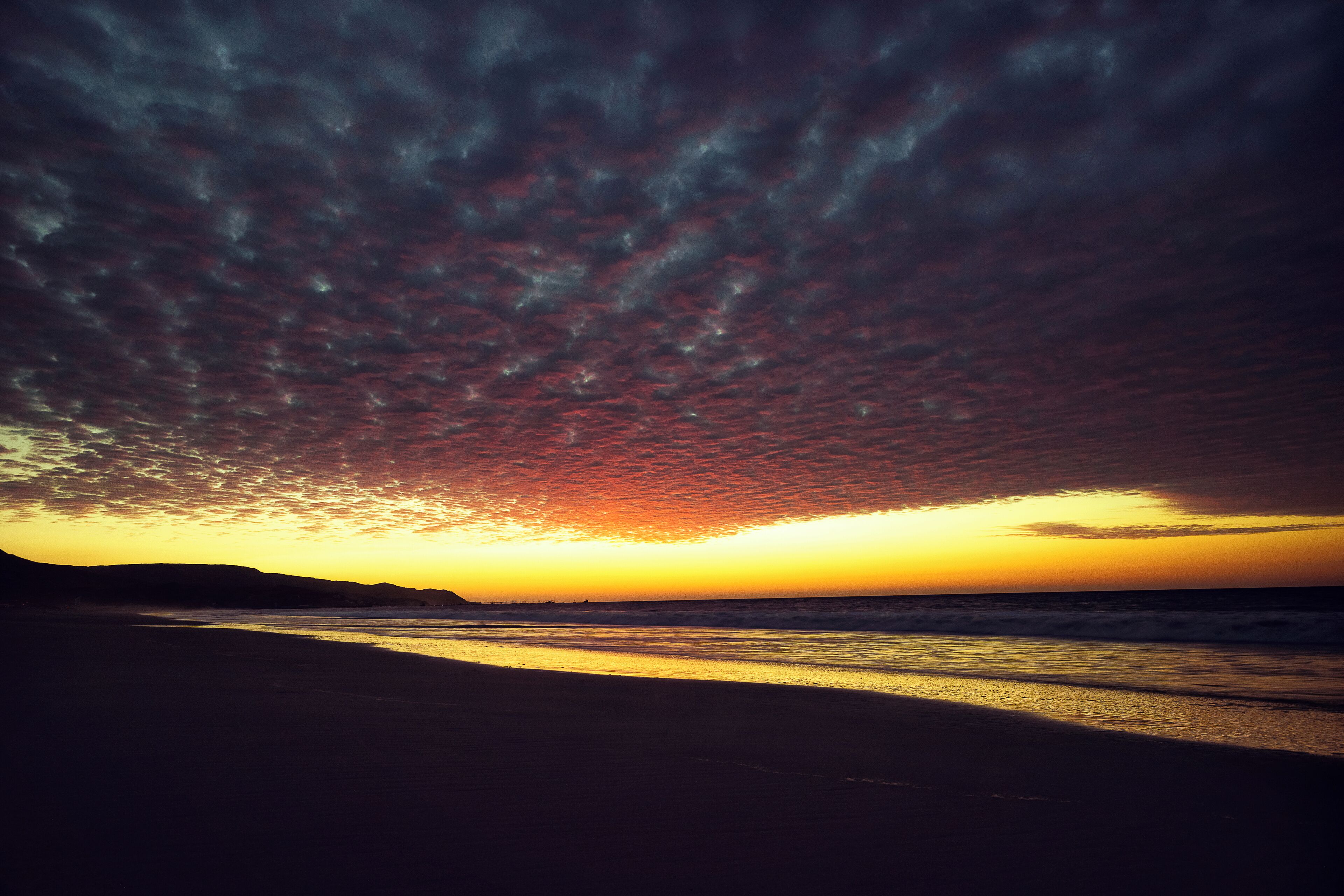 Una playa al atardecer con un cielo espectacular.