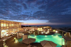 A resort with a swimming pool, outdoor seating, and a view of the ocean at dusk. - Norte Suites Boutique (Los Organos)