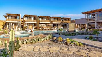 Un resort con edificios de varios pisos, piscina y jardines desérticos con cactus y rocas.