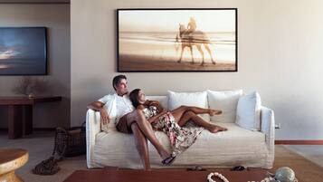 Una pareja descansando en un sofá blanco en una sala de estar con un cuadro de una escena de playa en la pared.