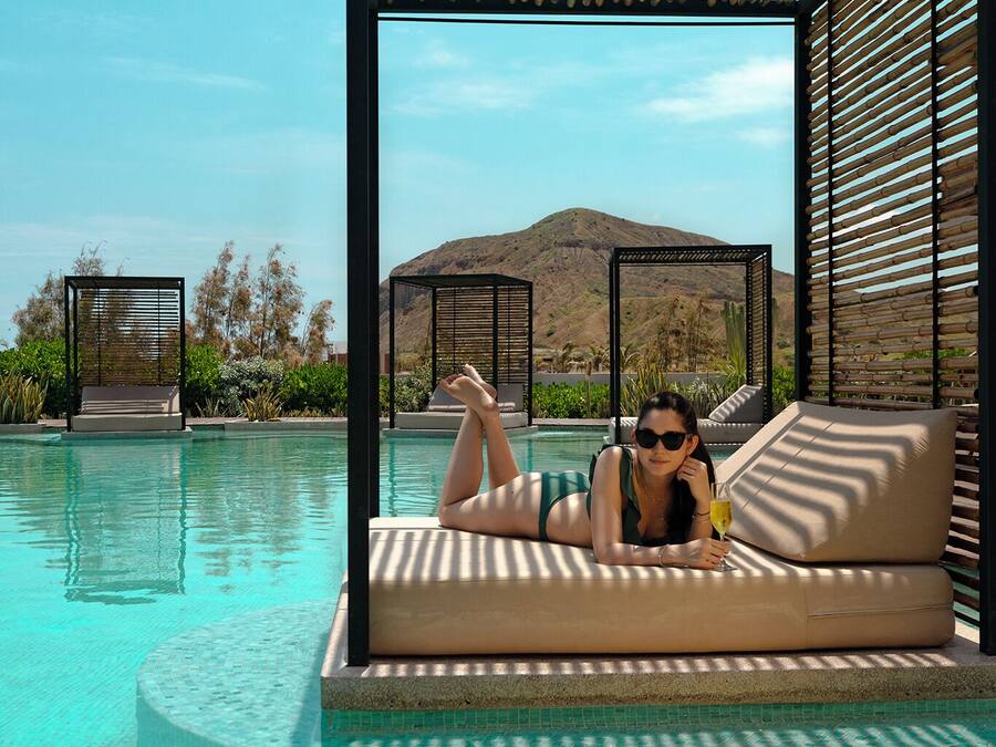 A poolside lounge with a view of a mountain and desert landscape.