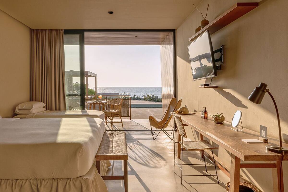 Una habitación de hotel con una cama grande, un escritorio y vistas al mar.