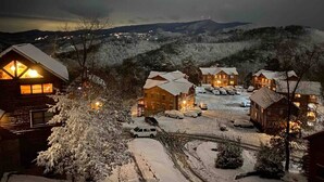 Un chalet enneigé composé de plusieurs bâtiments, avec un espace de stationnement et une vue sur le paysage environnant.