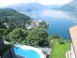 A view of a lake with a town on the shore, a swimming pool, and surrounding greenery. - Palma Romantic Dream (Perledo)