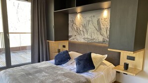 Un dormitorio moderno con una cama grande, vistas del exterior a través de una puerta corredera y una decoración de pared con motivos de montaña.