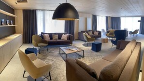 Una sala de estar moderna con un sofá, sillones, una mesa de centro y una lámpara colgante grande.