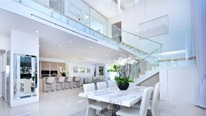 A modern, spacious interior with a large dining area, a kitchen, and a staircase leading to an upper level.