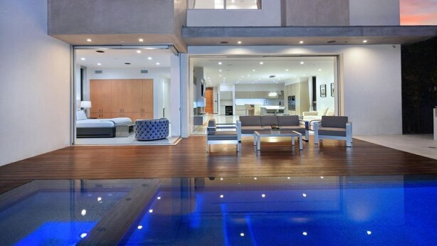 A modern interior with a glass-enclosed pool, wooden flooring, and contemporary furniture.
