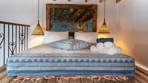 Een bed met een beddekleed met patroon, twee kussens en een stapel handdoeken.