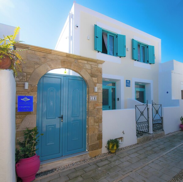 A building with a blue door, stone archway, and a sign indicating a traditional inn. - Koskinou Traditional House (Rhodes)