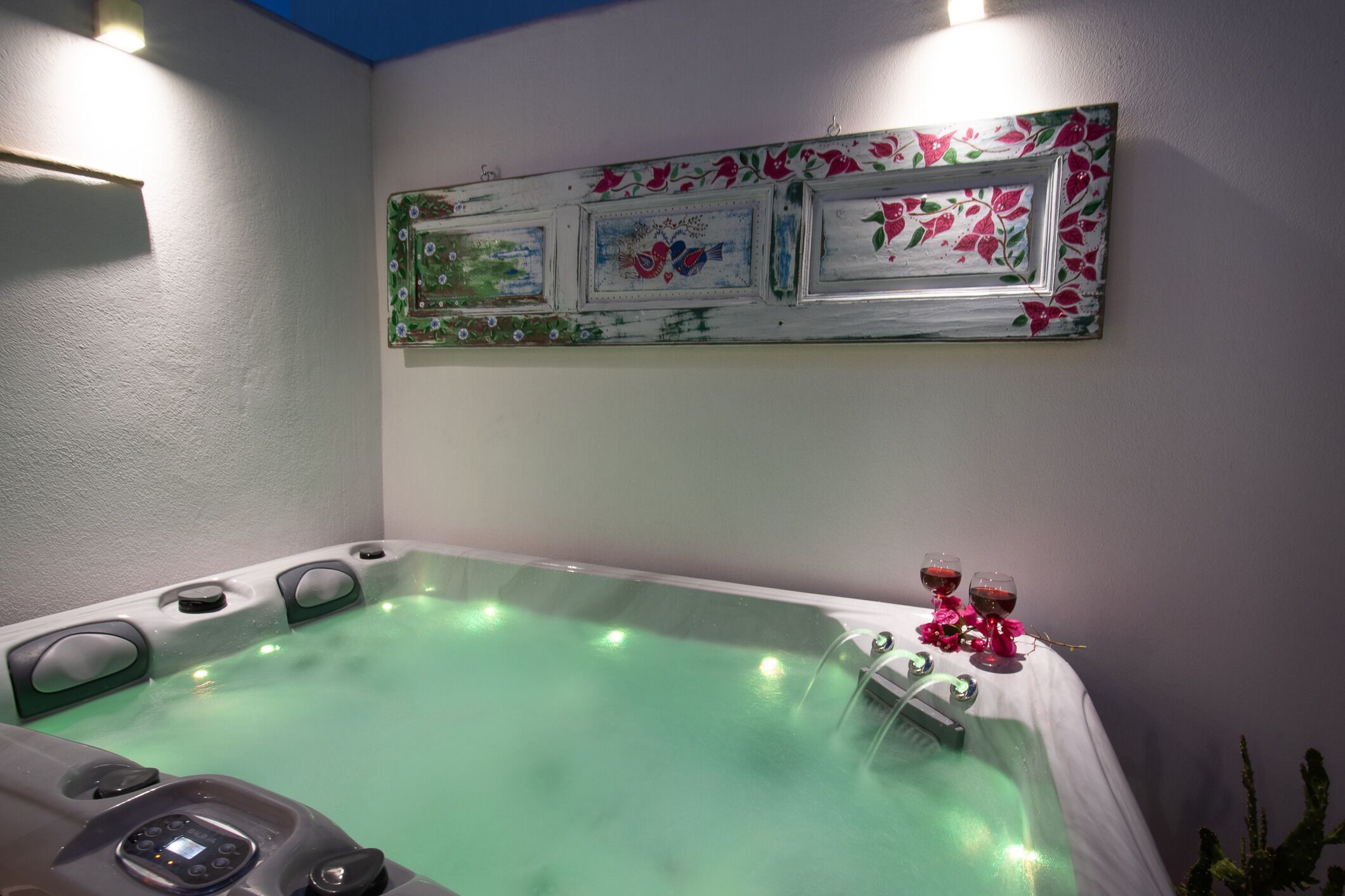 A spa area with a hot tub, control panel, and decorative wall art.