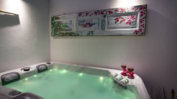 A spa area with a hot tub, control panel, and decorative wall art.