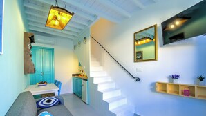Een modern interieur met een trap, een bank, een keukenhoek en een aan de muur bevestigde televisie.