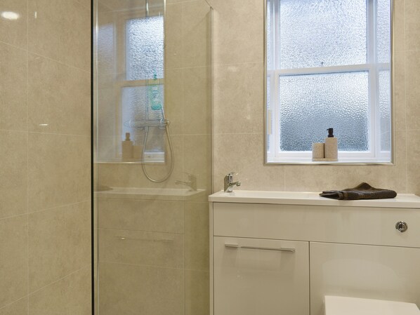 A bathroom with a glass shower enclosure, a sink with a towel, and a window with a view. - 2 bedroom accommodation in Banchory (Banchory)
