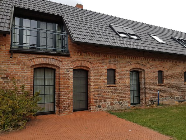 A brick building with large windows and a sloped roof.