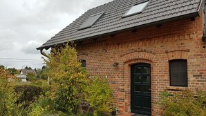 Una casa de ladrillo con techo inclinado, una puerta negra y una ventana pequeña.