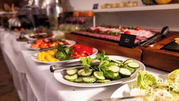 En buffet med forskellige retter, herunder skivede agurker, tomater og ost.