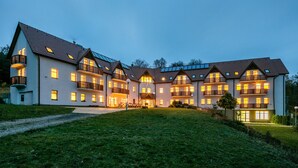 A multi-story hotel with balconies, a covered walkway, and a well-maintained lawn.