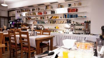 A restaurant with wooden tables and chairs, a coffee machine, and shelves with books and food items.