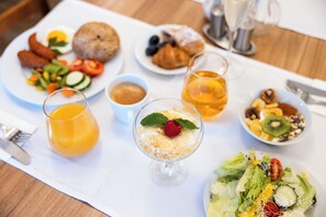 A breakfast setting with various dishes, including eggs, pastries, and a fruit salad. - Pytloun Wellness Hotel Hasištejn (Misto)