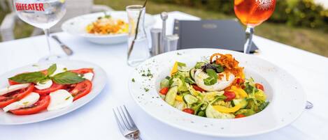 Una mesa servida con dos platos de comida, una bebida y una carta.