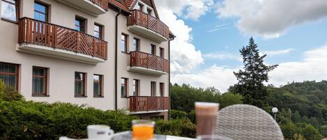 Una mesa de comedor con alimentos para el desayuno y vistas a un edificio de varios pisos con balcones.