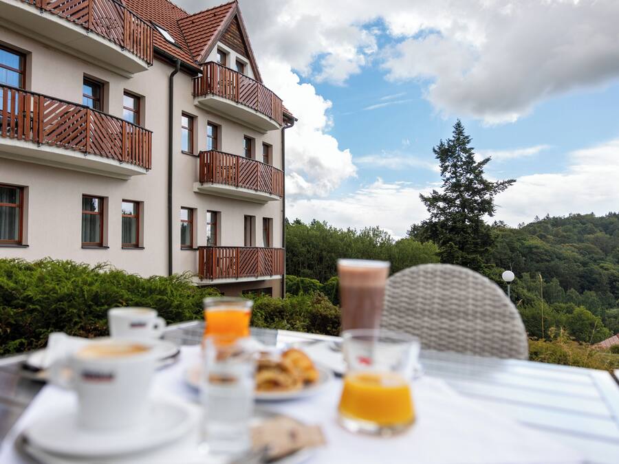 A dining table with breakfast items and a view of a multi-story building with balconies.