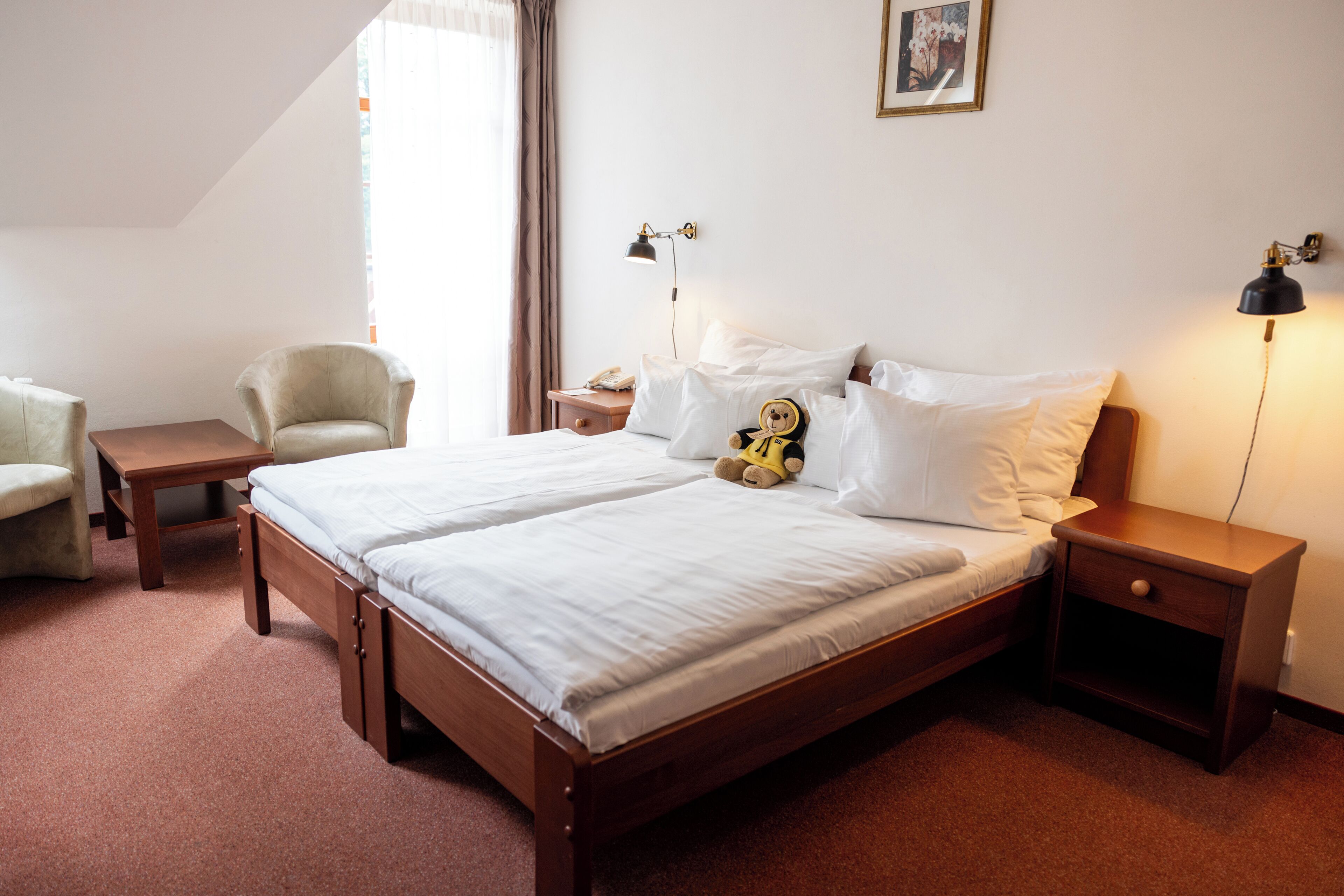 Een hotelkamer met een tweepersoonsbed, nachtkastjes, een stoel en een bureau.
