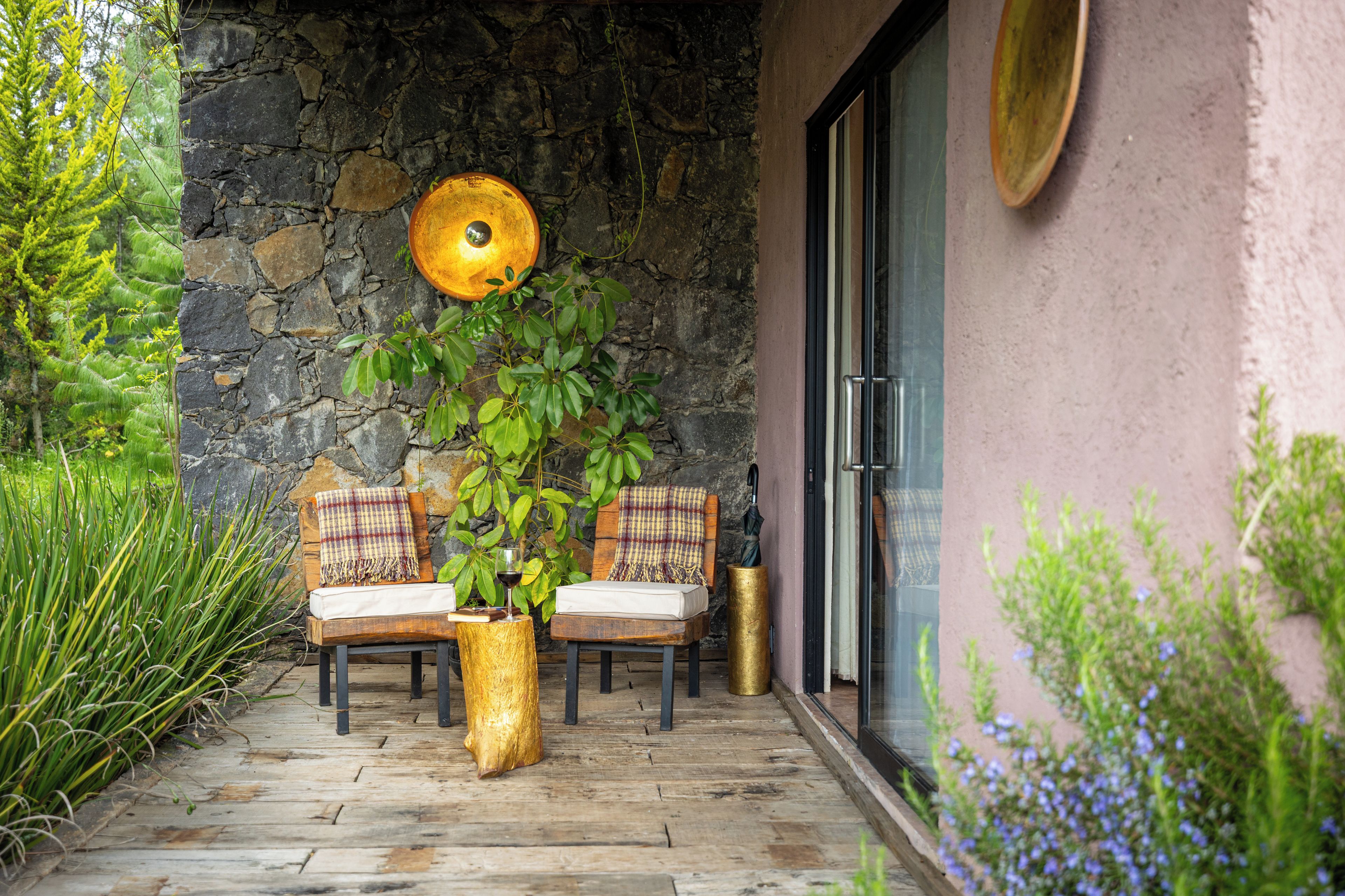 Une terrasse avec deux chaises en bois, une table et un pot de fleurs.