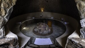 A stone-walled hot tub with a central fire feature, surrounded by seating and towels. - Casa Maria Campiña (Jilotepec)