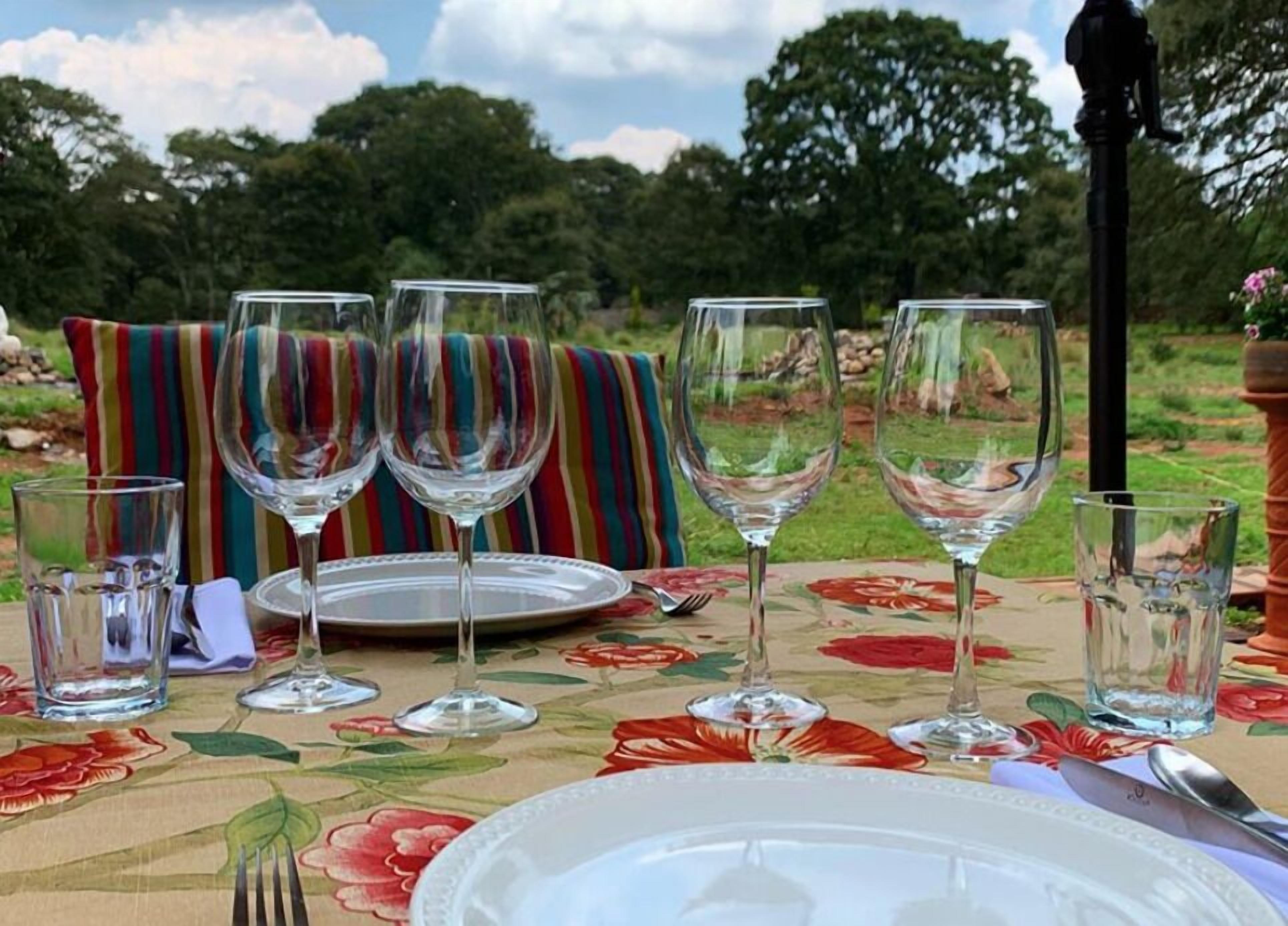 A table set for a meal outdoors with wine glasses, plates, and cutlery.