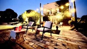 Un espace extérieur aménagé avec un sol en bois, deux chaises et une table.