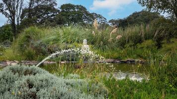 A garden with a water feature, including a statue and various plants.