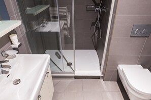 A modern bathroom with a glass-enclosed shower, a white sink, and a toilet.