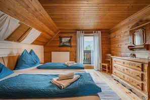 A wooden cabin room with two beds, a dresser, a chair, and a window with a view of mountains. - Beautiful wooden log house with a first-class view of the mountains! (Bad Goisern am Hallstättersee)