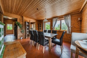 A wooden cabin interior with a dining area, a kitchen, and a living space. - Beautiful wooden log house with a first-class view of the mountains! (Bad Goisern am Hallstättersee)