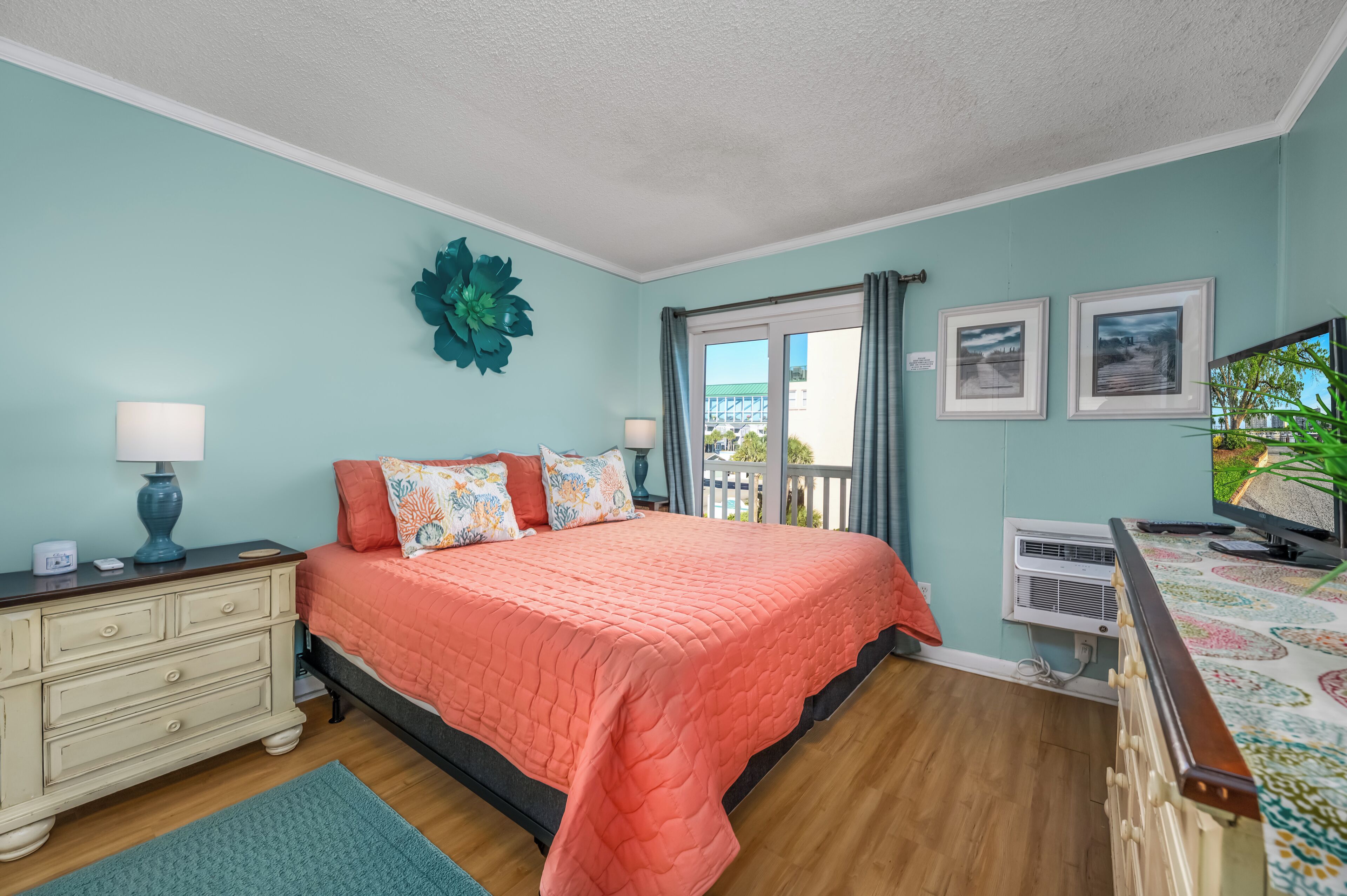 A bedroom with a bed, dresser, and a window with curtains.