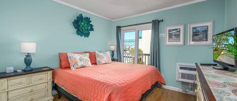 A bedroom with a bed, dresser, and a window with curtains.