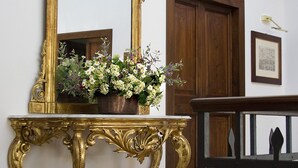 A room with a large ornate mirror on a golden console table, a wooden door, and a framed picture on the wall. - Luxury Villa with private pool and Estate Winery in Umbria (Orvieto)