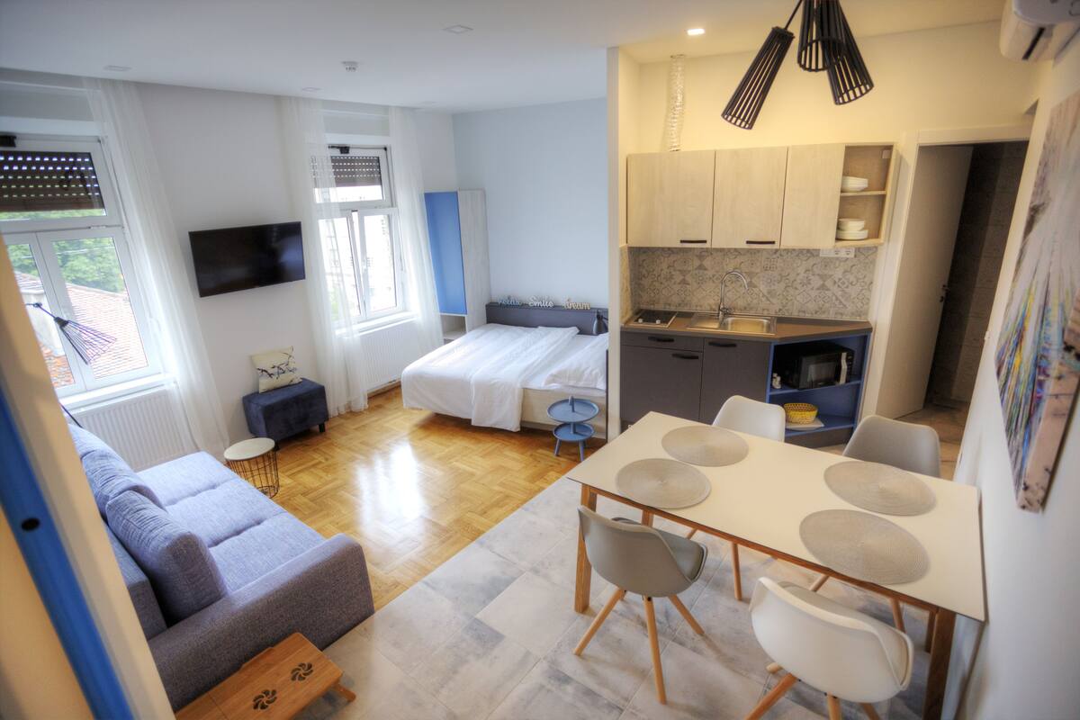 Ein gemütlicher, kompakter Wohnbereich mit Bett, Sofa, Esstisch und Küchenzeile.