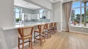 A modern kitchen with white cabinets, a central island, and bar stools.