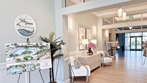 A spacious lobby with a reception desk, white chairs, and artwork on easels.